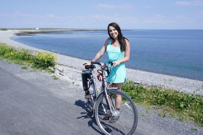 a woman riding a bicycle next to a body of water