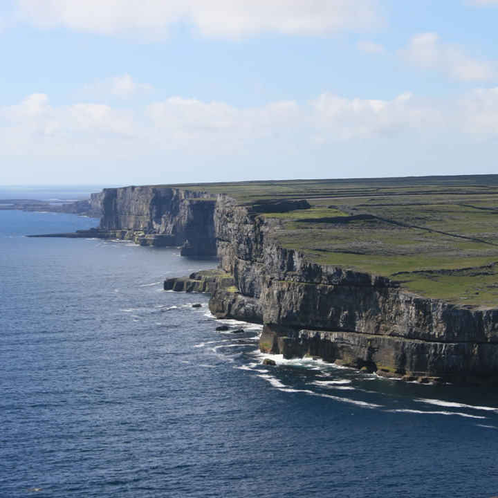 a large body of water with Cliffs of Moher in the background