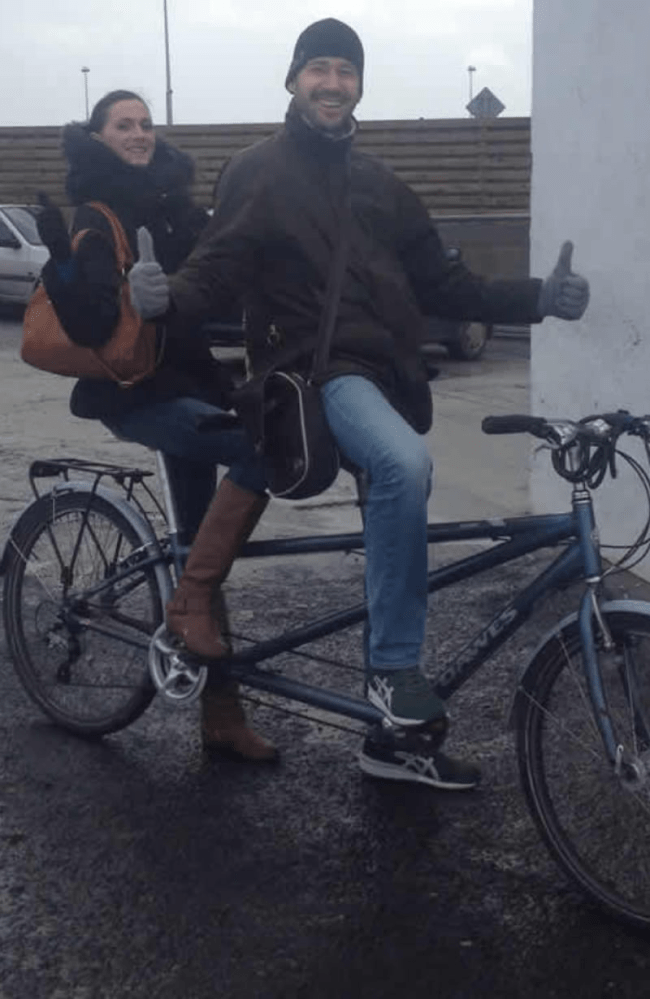 a man and a woman riding on the back of a bicycle